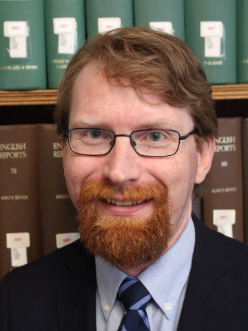 Front facing photograph of Steven Mitchell in front of a bookcase