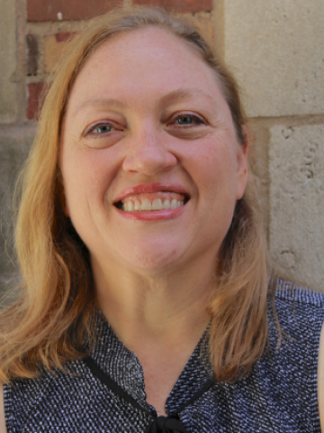 Woman smiling against back drop of a brick wall