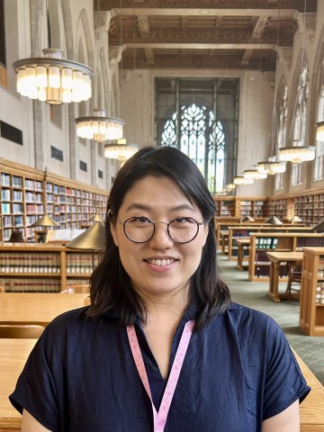 Smiling woman in glasses standing in a library. 