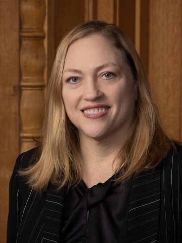 A woman smiling in front of wood paneling.