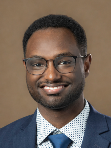 Man in glasses smiling into camera.