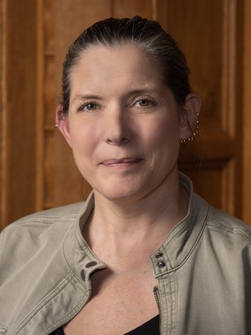A woman smiling in front of wood paneling.