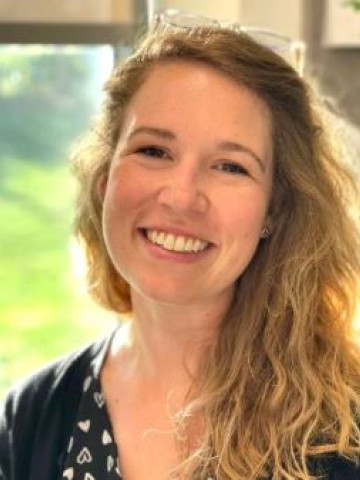 Woman smiling at camera in front of window. 