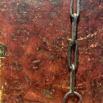 A brownish-red worn leather book cover with an small attached chain.