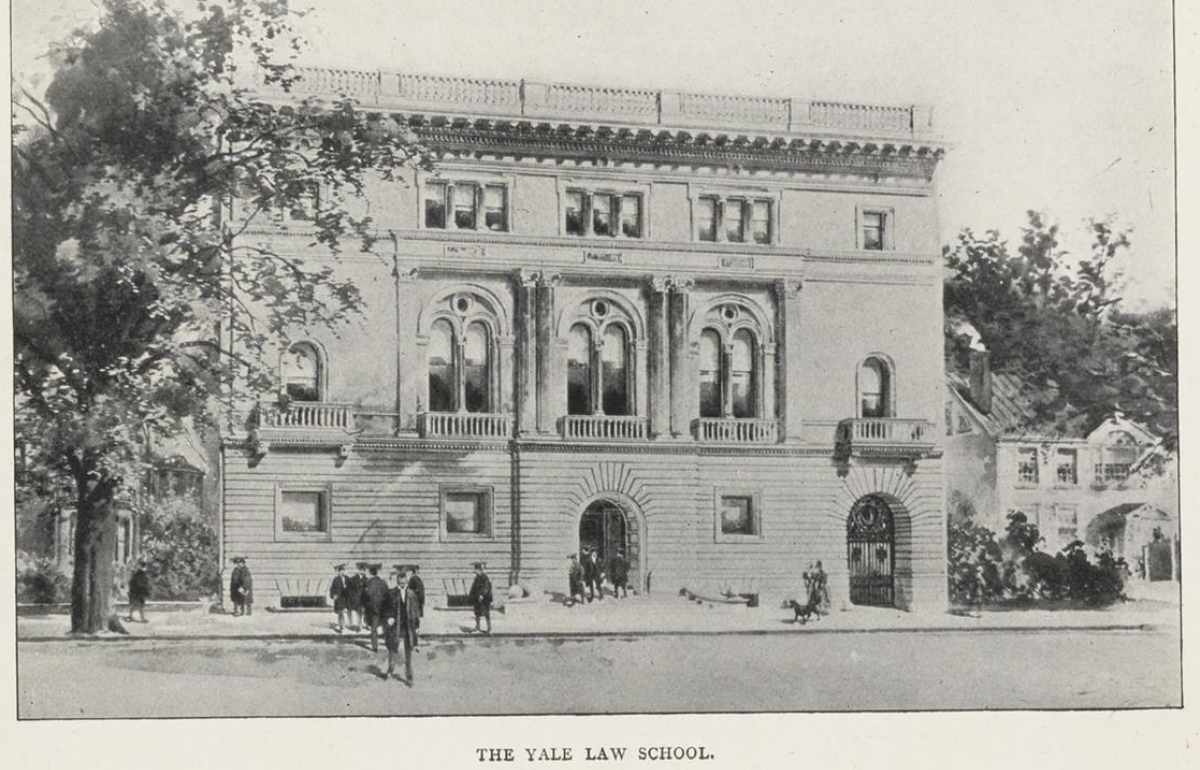 A black and white image from 1898 of a three story building with some people out in front