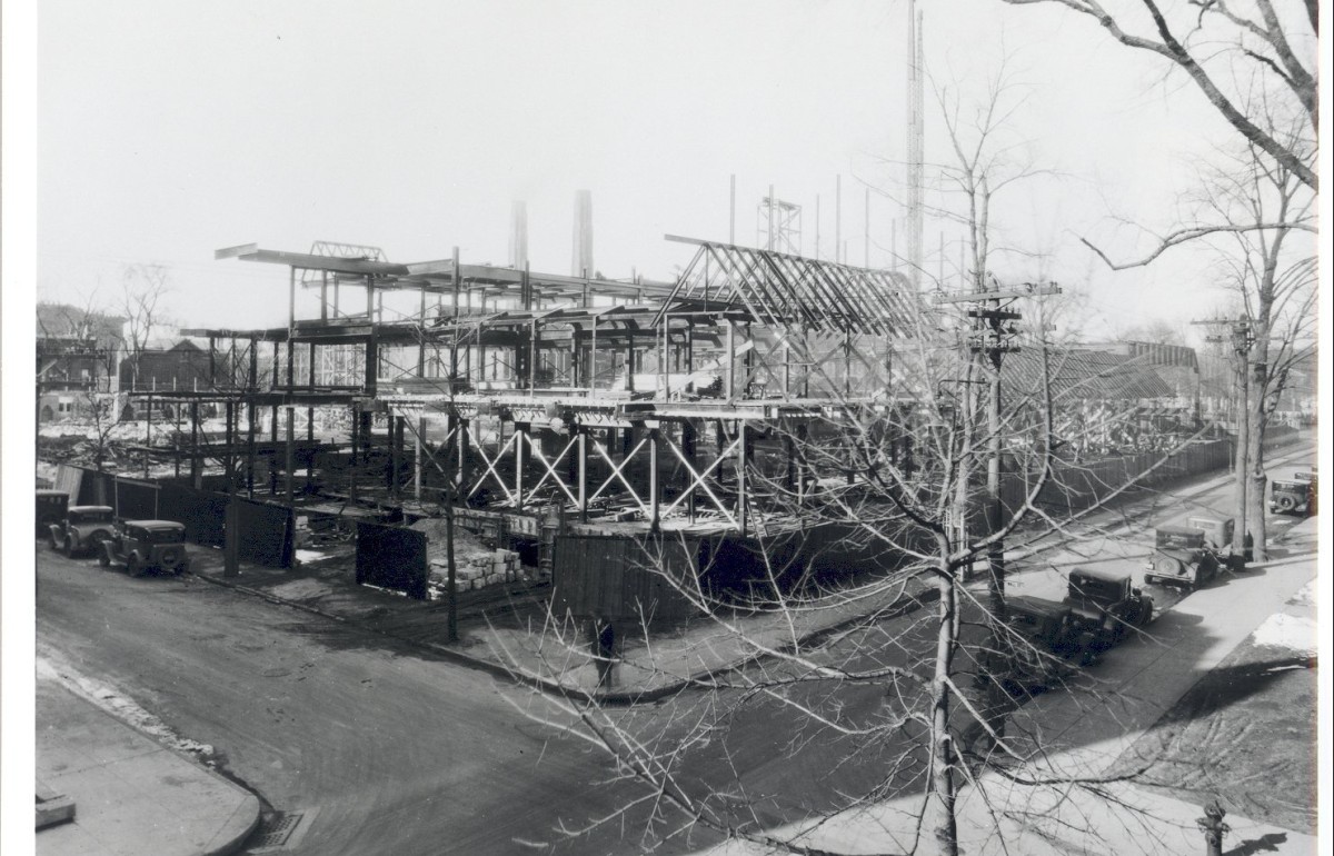 Black and white photograph of a road intersection with a partially built building on one corner