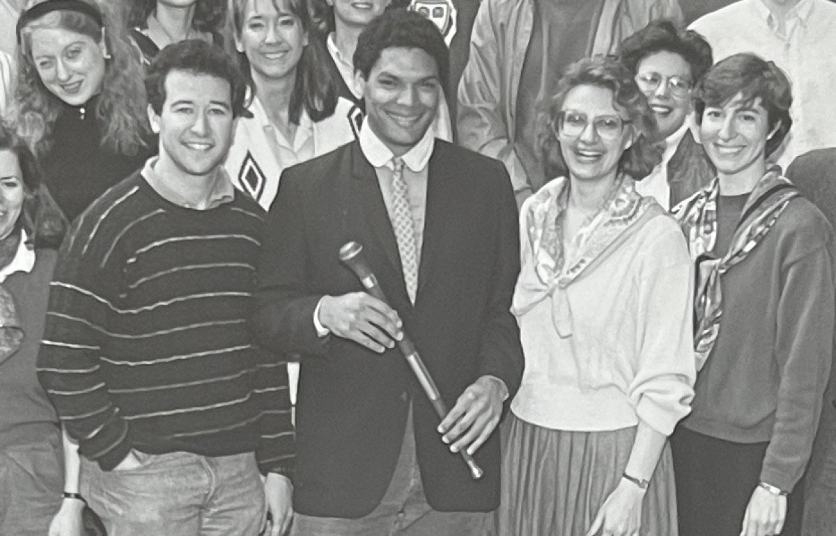 Group photograph with a man front and center holding a scepter. 