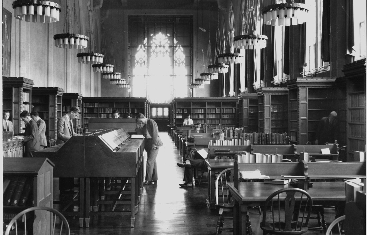 Long shot photograph of the law library with some scattered students.