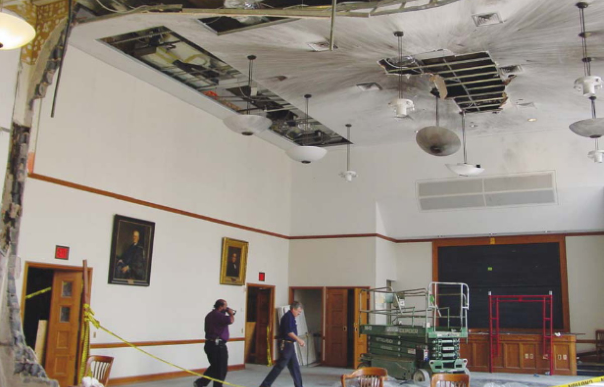 An room with construction equipment in it and dark bomb blast stains on the ceiling