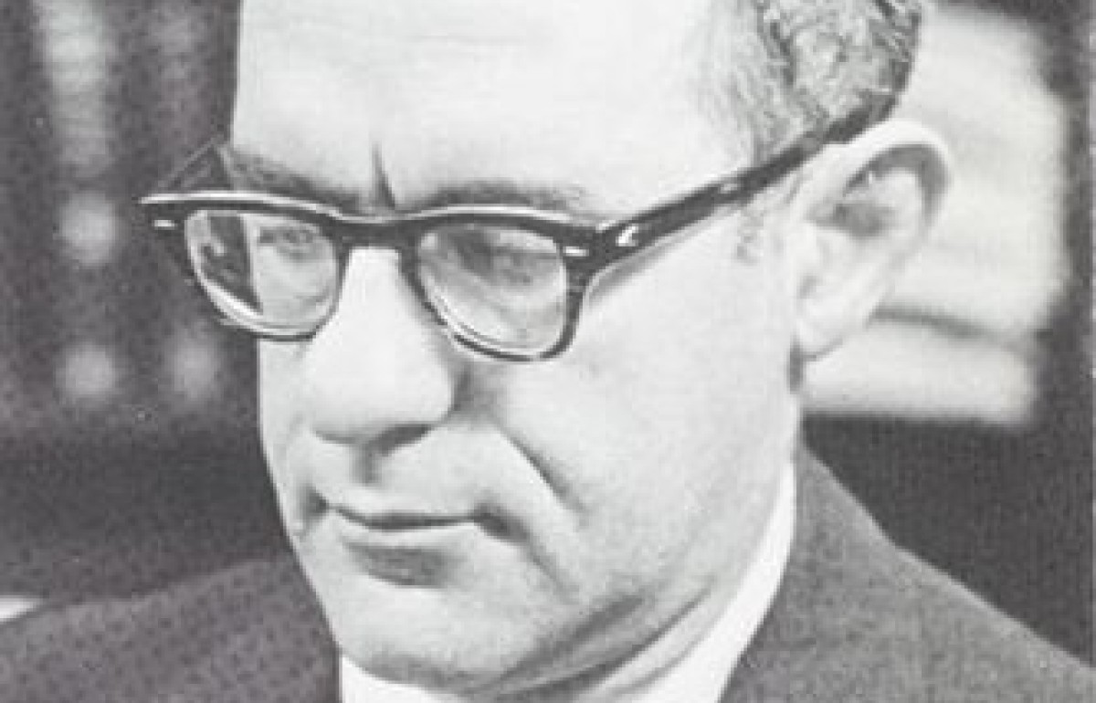 Black and photograph of a bespectacled man reading.