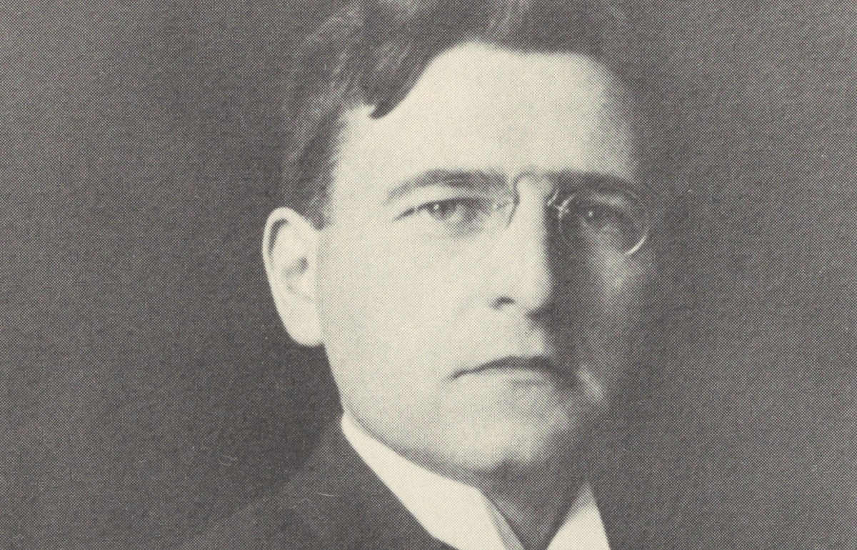 Yellowed bust-style photograph of a man with spectacles.
