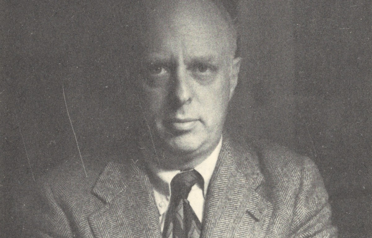 Heavily shadowed photograph of a front-facing man in a suit.