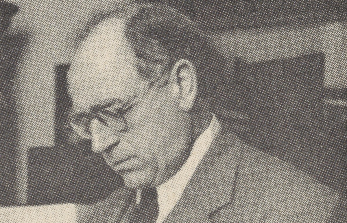 Yellowed newspaper photograph of a man in a suit reading