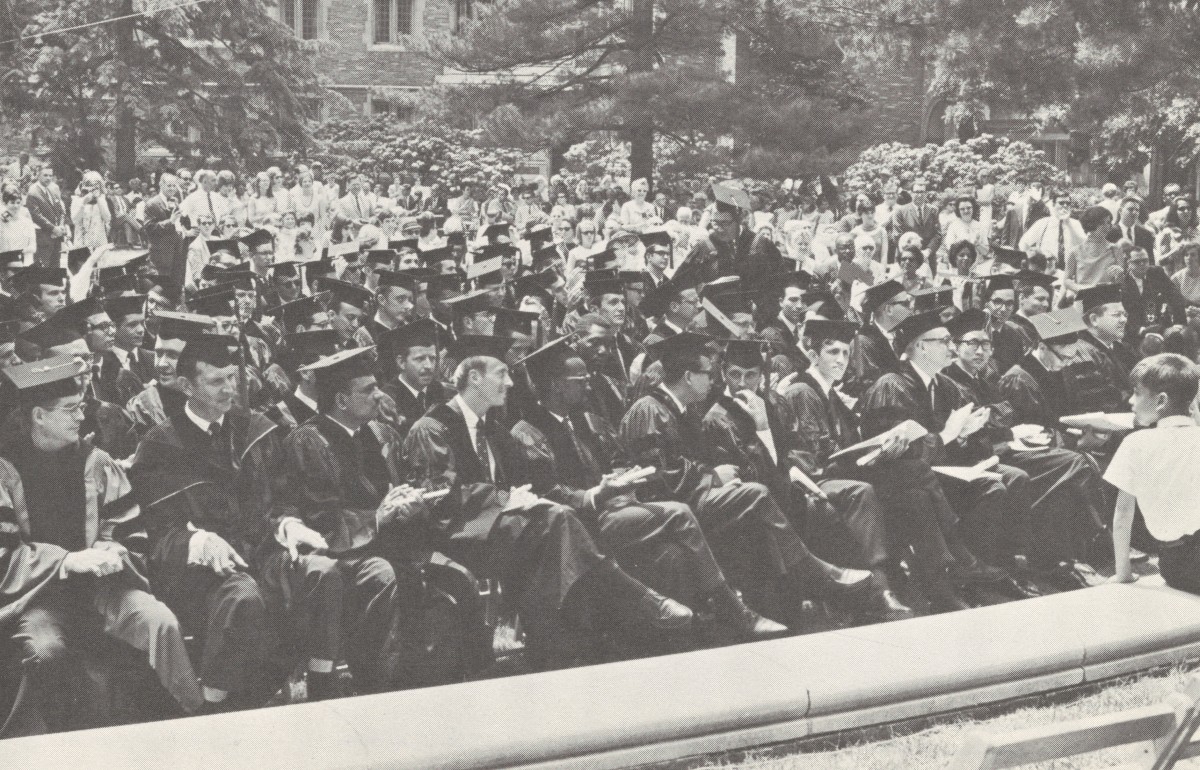 Photograph of a large crowd in graduation robes and caps