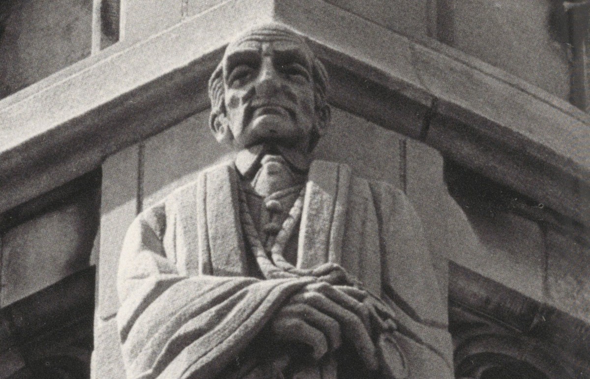 Black and white photograph of a carved stone man in a robe.